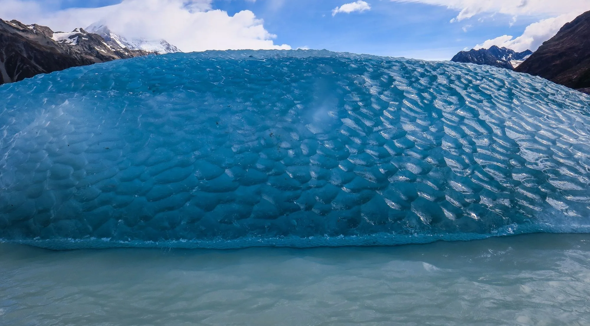 Close view of a scalloped blue iceberg in a glacier lake