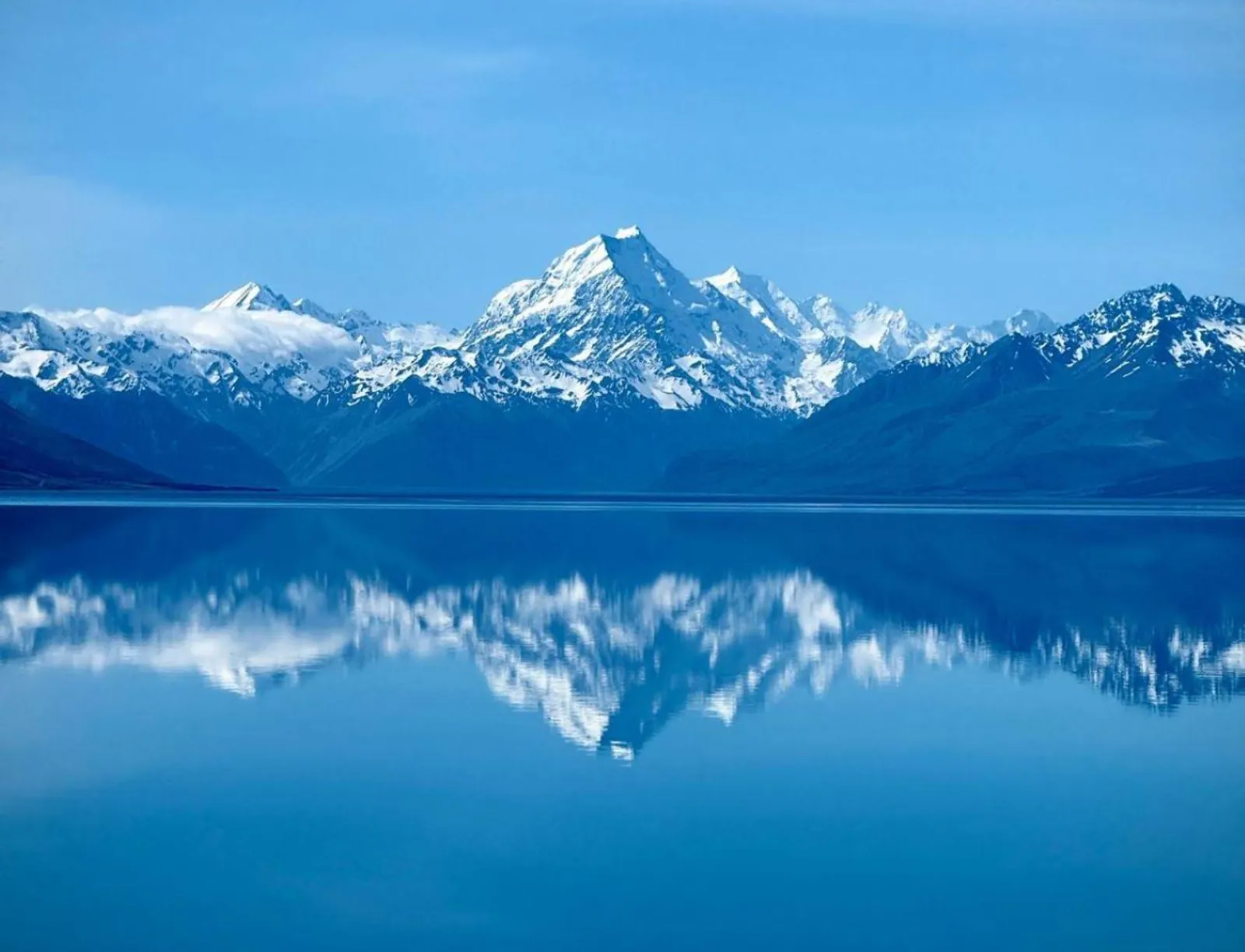Snow-capped Aoraki/Mount Cook mirrored in calm blue Lake Pūkaki