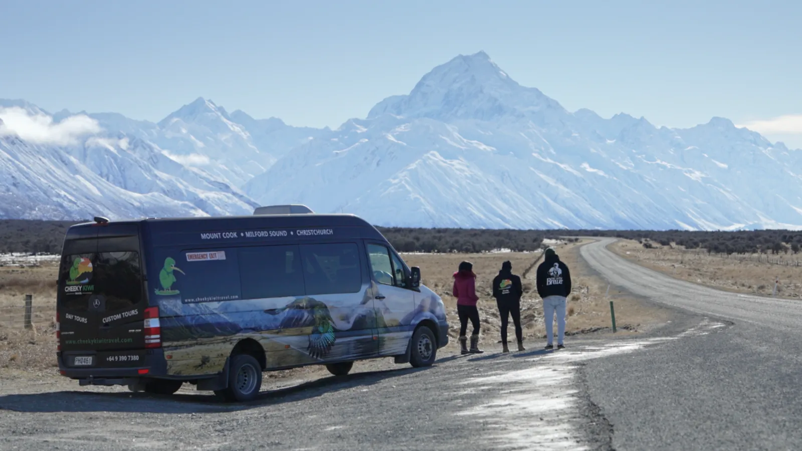 Cheeky Kiwi minibus pulled over on the road to Mount Cook as passengers look at snow-covered Aoraki