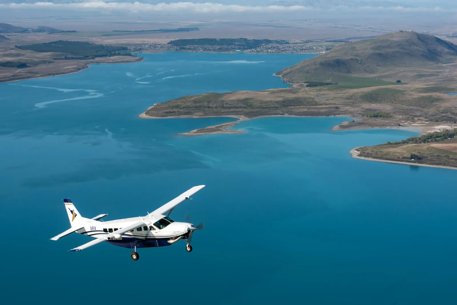 Air Safaris plane over the blue water of Lake Tekapo, with the township and Mount John beyond
