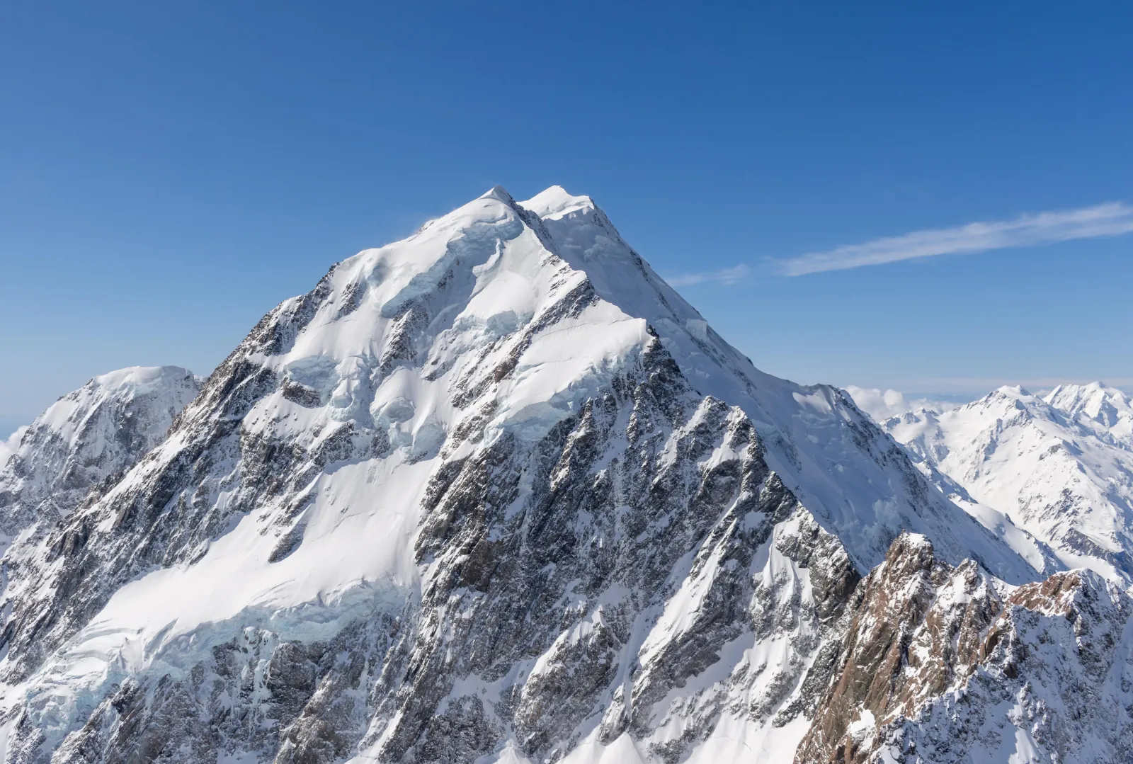 Snow-covered summit of Aoraki/Mount Cook against a clear blue sky, seen from the air