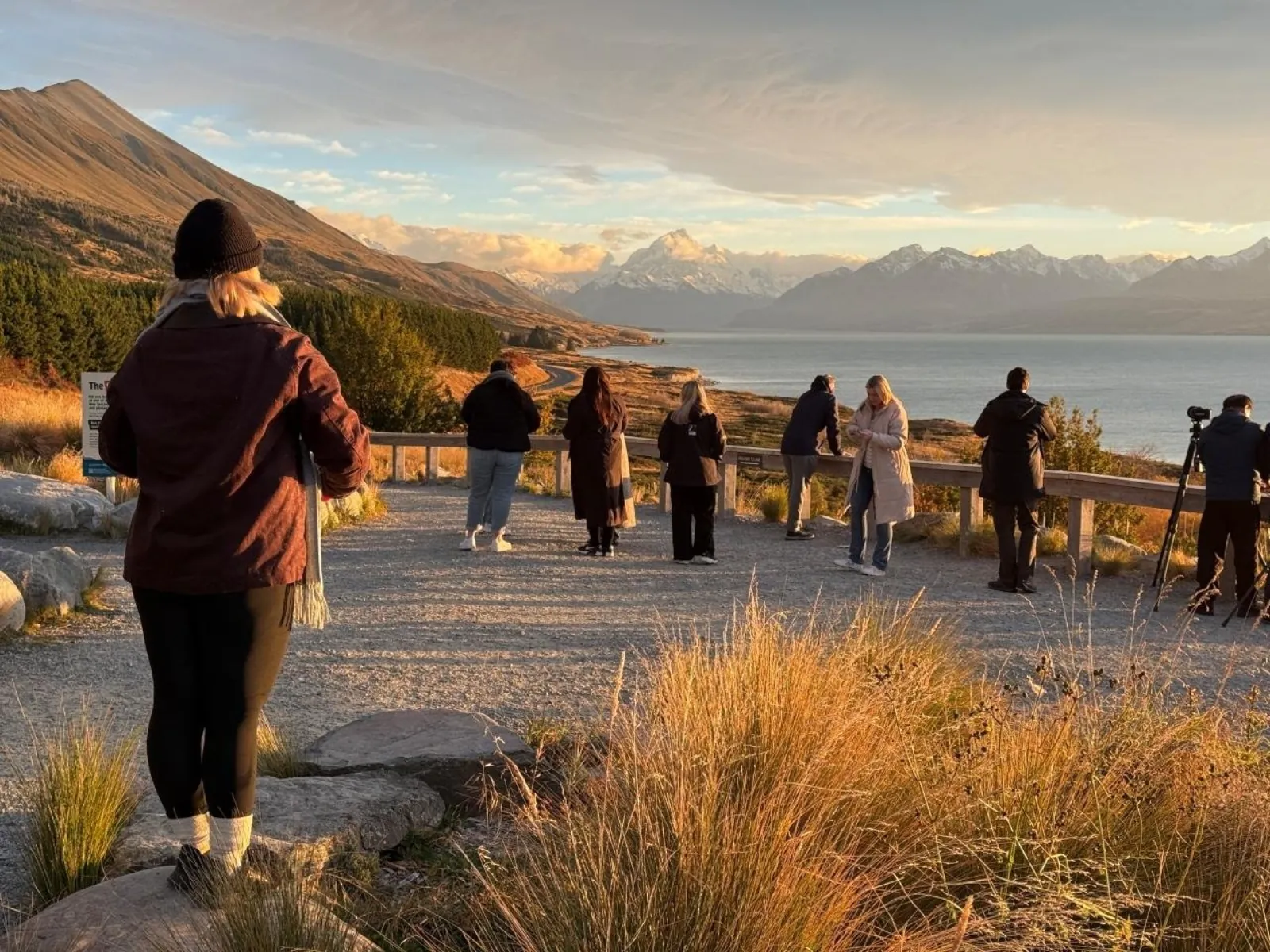 Tour group at the Lake Pūkaki lookout watching golden light on Aoraki/Mount Cook