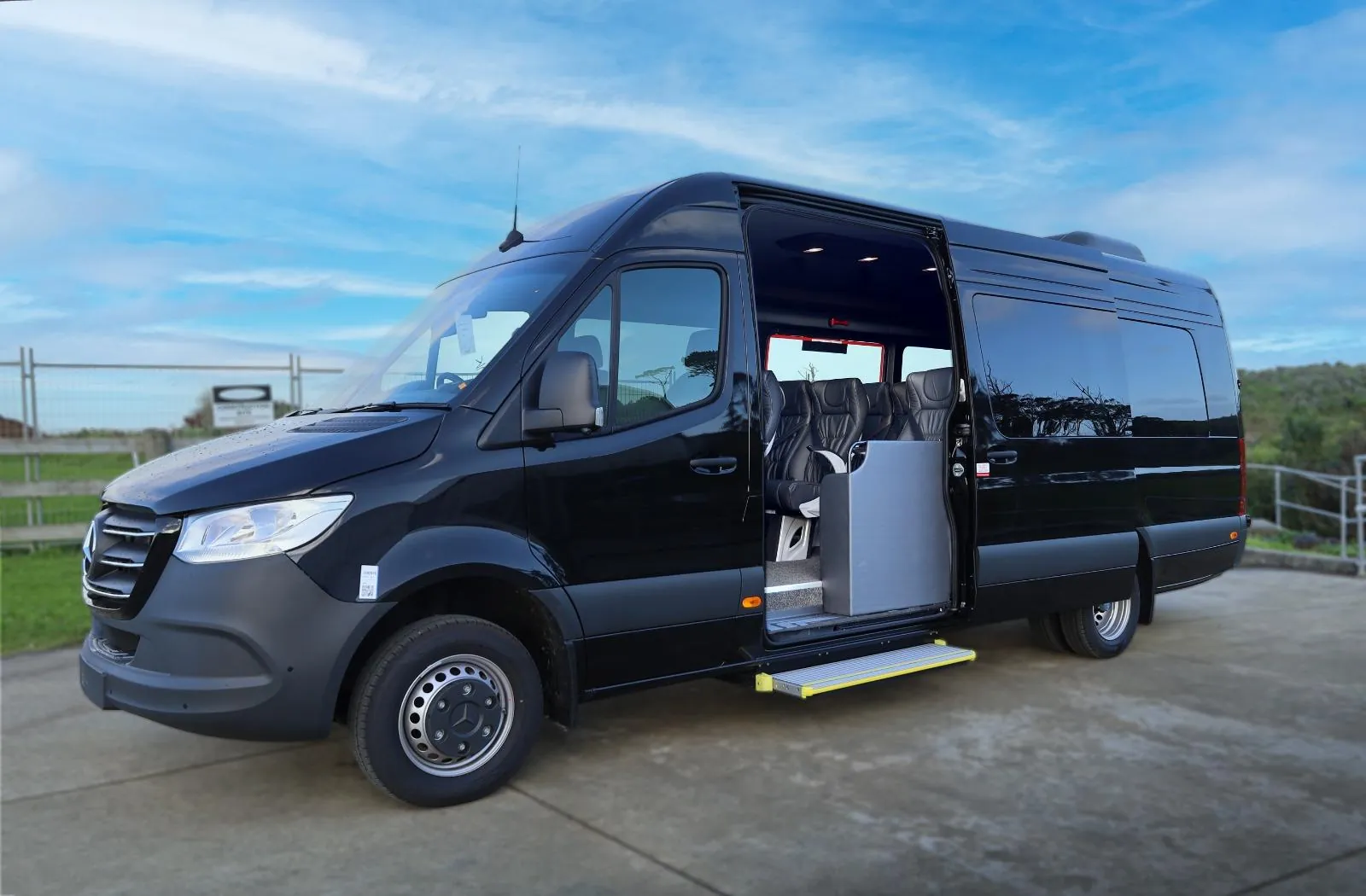 Black Mercedes Sprinter tour minibus with its side door open to leather seats
