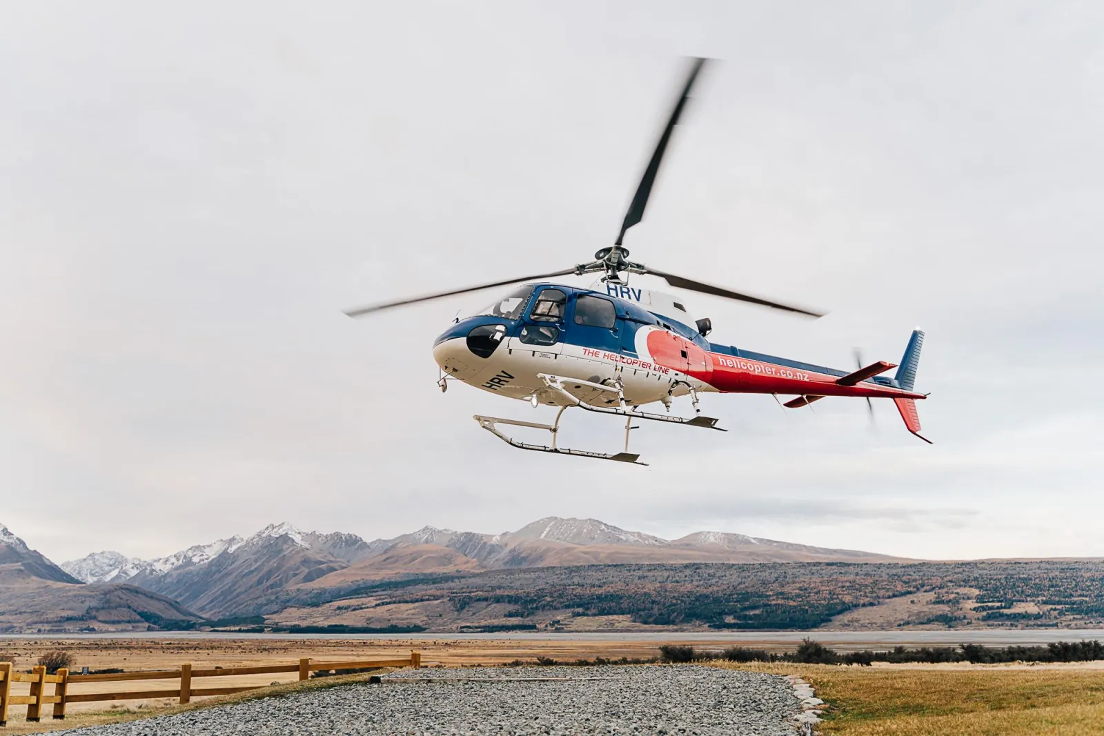 The Helicopter Line helicopter lifting off from the Glentanner Park pad, high-country ranges behind