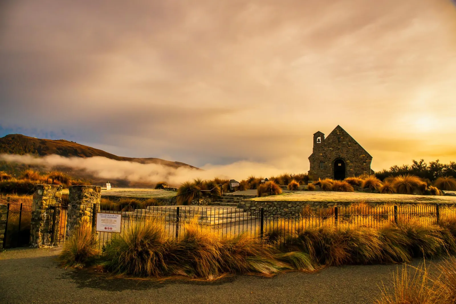 Church of the Good Shepherd at Lake Tekapo in golden morning light, with mist over the hills behind