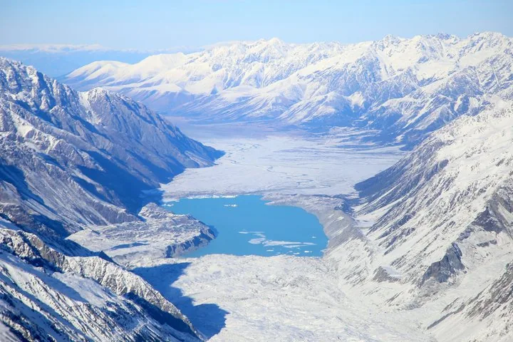 Aerial view of Tasman Lake with floating icebergs at the foot of the Tasman Glacier, snowy ranges beyond