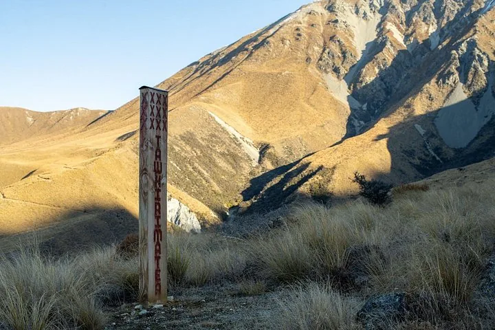 Carved wooden marker post beside the track on Glentanner Station's golden tussock hillsides