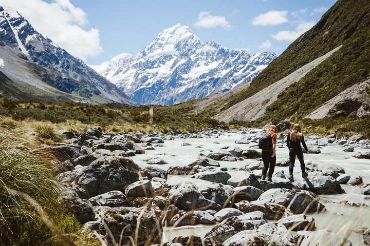 Walkers crossing the rocky bed of the Hooker River with Aoraki/Mount Cook ahead